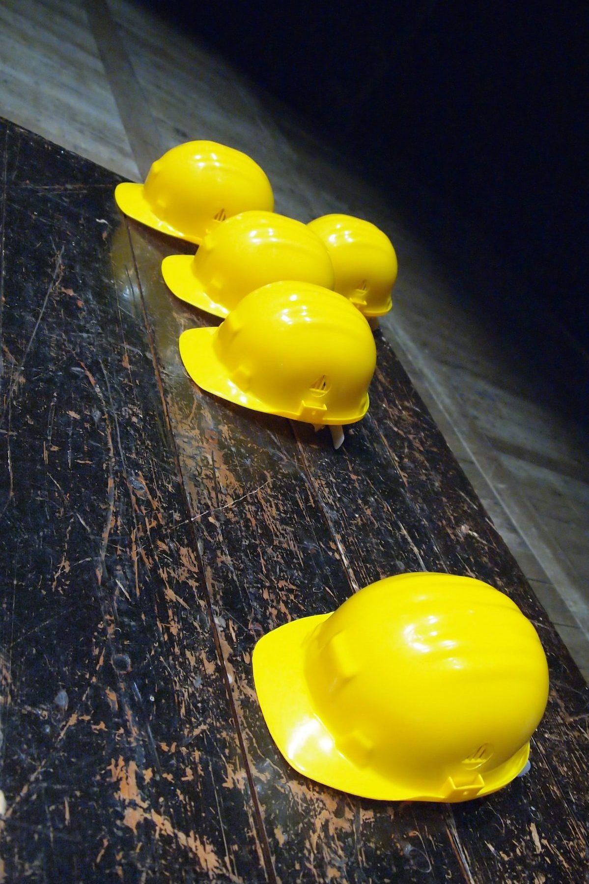 five yellow hard hats on gray surface